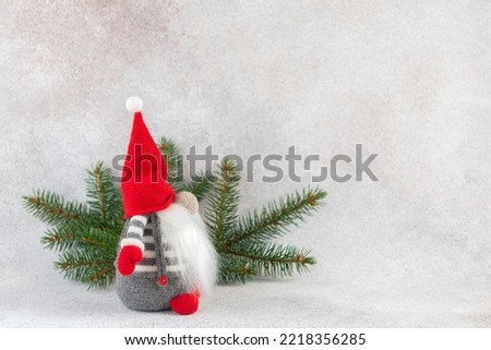 Christmas gnome in red hat side view with fir branch holiday card on light winter background. Scandinavian elf greeting card with copy space