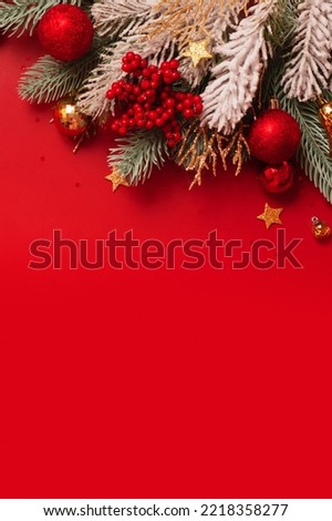 Christmas decoration and pine tree on red background with copy space. New Year greeting card. Flat lay. Vertical format.