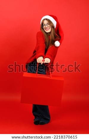 Christmas discount, young cheerful woman with a shopping bag on a red background, vertically. New Year's sales.