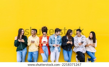 Multiracial young friends having fun sharing media content on mobile phone - Millennial diverse people using smart phone together leaning against wall - Social media trends and technology concept Royalty-Free Stock Photo #2218371267