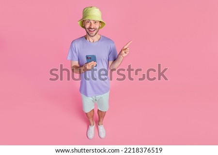 Full body photo high angle view of nice young man point empty space hold gadget wear stylish blue garment isolated on pink color background Royalty-Free Stock Photo #2218376519