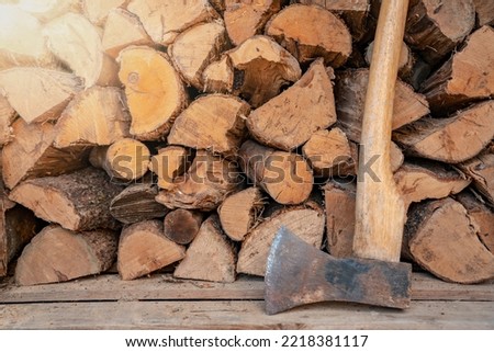 Axe in front of a stack of wood in a woodshed. Natural background.