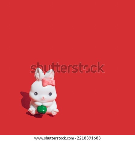Little white rabbit on vibrant red background. Symbol of the Chinese New Year of the rabbit. Happy 2023 and good luck!