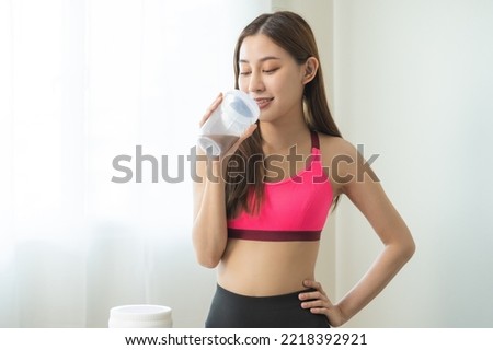 Diet meal replacement for weight loss, happy asian young woman, girl in sportswear, hand in holding protein shake bottle for drink supplement for muscle after workout at home. Healthy body care person Royalty-Free Stock Photo #2218392921