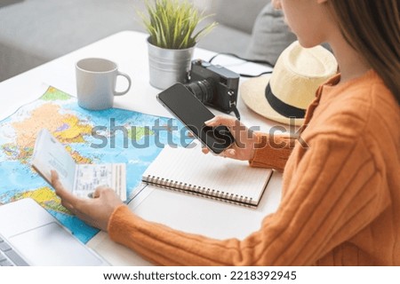Travel planning, vacation, holiday trip, asian young tourist woman, girl hand using mobile phone, cellphone book flight ticket or check in online with passport, preparation for journey voyage trip.