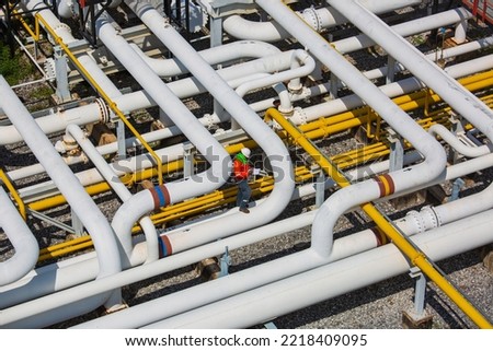 Top view male worker inspection at steel long pipes and pipe elbow valve in station oil factory during refinery valve of visual check record pipeline oil and gas industry. Royalty-Free Stock Photo #2218409095