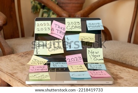 New year 2023 goals and resolution written on a sticky notes pasted on a laptop