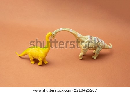 Two dinosaurs on a brown background. Plastic toys. Minimal design.