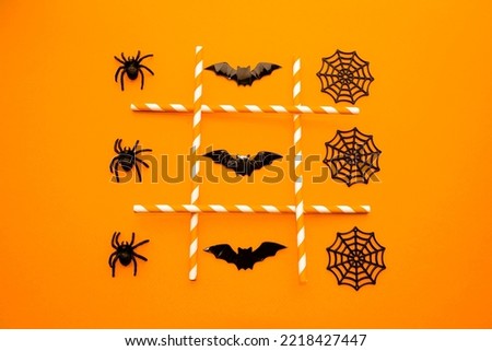 On an orange background, a festive game for Halloween.  Figurines symbols of the holiday lie in a row of black spiders, cobwebs and bats.  The concept of entertainment, the development of thinking.  