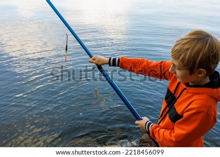 hands of a boy who holds in his hands a fishing rod with a fish caught on the hook