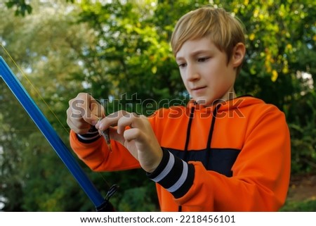 in the hands of the boy a fishing rod and a fish that he takes off the hook while fishing