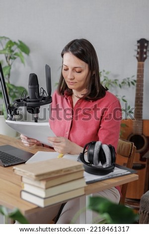 woman in a home office records podcast audio content with a microphone and headphones and a labrador dog. a young successful female journalist or radio presenter records music or broadcasts on the
