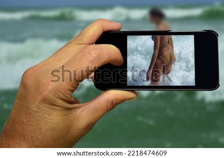 A voyeur secretly records a woman bathing with a smartphone Royalty-Free Stock Photo #2218474609