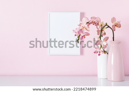 Beautiful flowers composition.  Photo frame, bouquet pink orchids in vase on table. Pink phalaenopsis orchid flower on pastel pink background. 