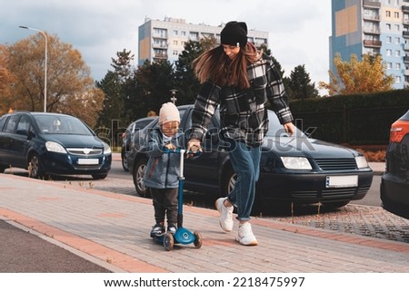 Mother and son having fun. Happy family mother teaches child son to ride a scooter in the city street. Support childhood parenthood idea. happy family concept.