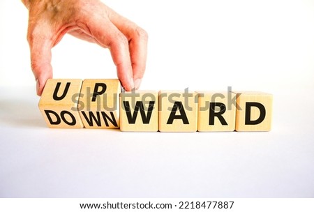 Upward or downward symbol. Businessman turns wooden cubes and changes the word 'downward' to 'upward'. Beautiful white table, white background. Business, upward or downward concept. Copy space.