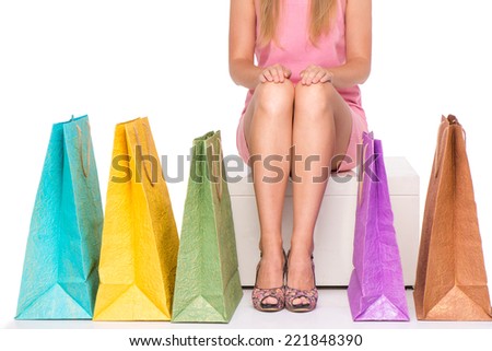 Close-up of sitting girl with row of colorful shopping bags, isolated on white background