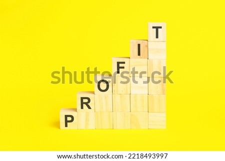 the word profit is written on a wooden cubes pyramide. blocks on a bright yellow background