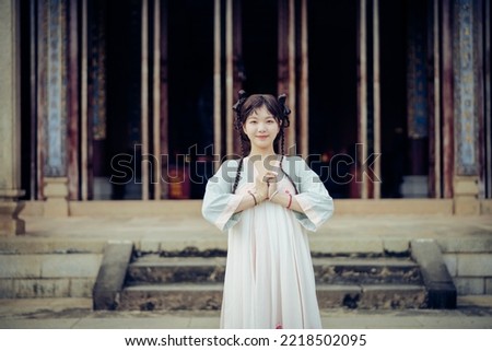 The girl in traditional Chinese dress is in the garden