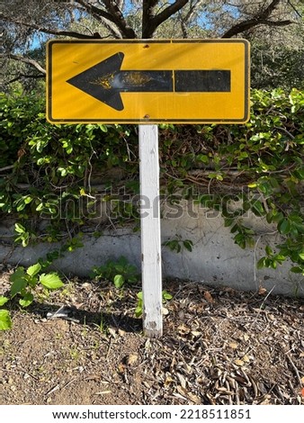 Black arrow to the left on a yellow road sign at the end of a street