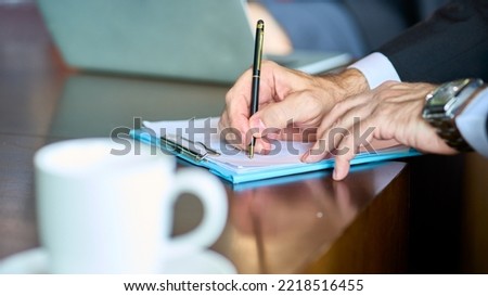 Businessman writting note on paper on working office and coffee cup on table , Business Office concept.