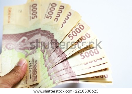 People holding Indonesia banknotes of 5000 rupiah. isolated on white background. perfect for photo illustration for business and finance articles. 