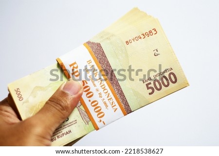 People holding Indonesia banknotes of 5000 rupiah. isolated on white background. perfect for photo illustration for business and finance articles. 