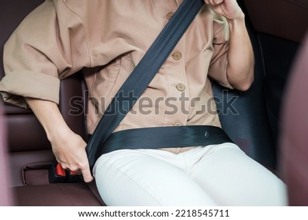 woman driver hand fastening seat belt during sitting inside a car and driving in the road. safety, trip, journey and transport concept Royalty-Free Stock Photo #2218545711