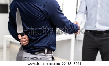 Back view of businessman shaking hands with another businessman while holding a knife behind his back. Concept of back backstabbing in business, backstabbing between colleagues. Royalty-Free Stock Photo #2218548041