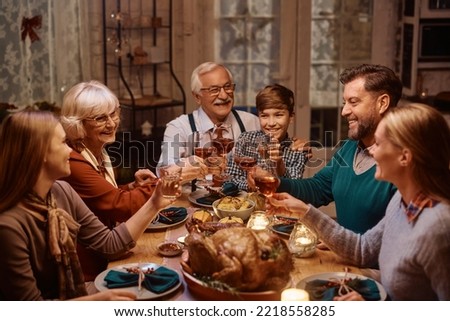 Happy multigeneration family toasting while having dinner at dining table on Thanksgiving. 