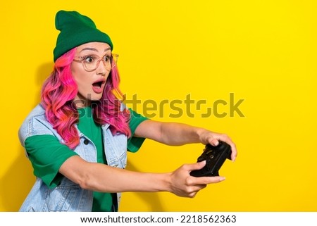 Portrait of excited gorgeous girl curly hairdo wear green t-shirt look empty space play video game isolated on yellow color background