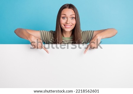 Photo of positive cheerful nice pretty woman with long hairstyle wear striped t-shirt directing poster isolated on blue color background