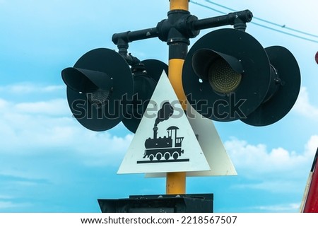 Guarded railroad crossing with open barriers, red warning light and cross 