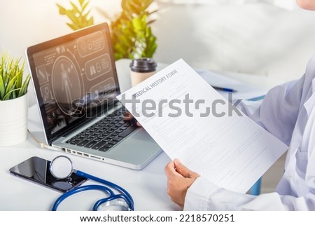 Doctor or nurse woman in uniform with stethoscope working she typing information of patient prescription from paperwork medical history form into laptop computer for record document data report