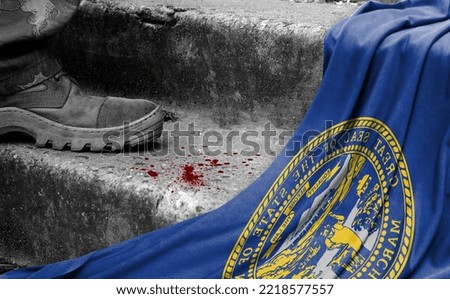 The leg of the military stands on the step next to the flag of State of Nebraska, the concept of military conflict