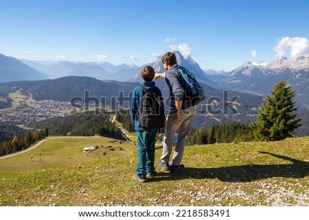 Hiking with children in Seefeld, Tyrol: Father shows his son the landscape. The snow-covered peak on the right edge of the picture is the Zugspitze