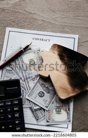 Dollar bills, calculator and a burn house on an insurance contract. Fire insurance concept. Vertical image.