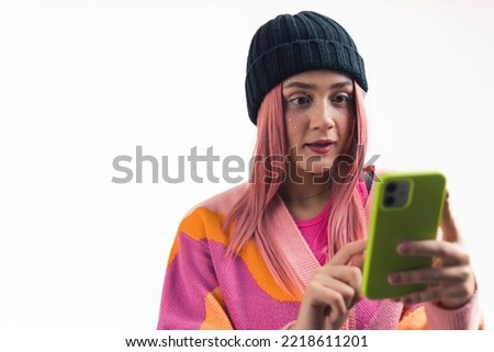 closeup studio shot of a young Caucasian pink-haired girl looking at something on the phone in surprise, white background. High quality photo