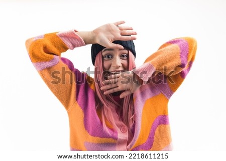 cheerful pink-haired girl smiling and holding her hands up near to her face, medium shot isolated indoors. High quality photo
