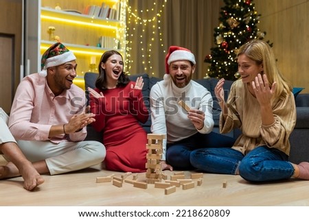 New year party, various friends at home on floor playing game, men and women smiling and happy together for christmas spend time.