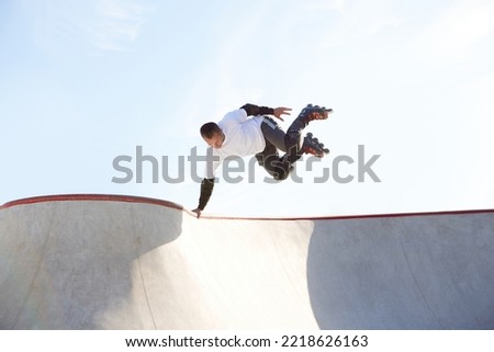 Energetic man on roller skates in motion at modern roller skate park. Professional roller skater doing dangerous and daring tricks. Concept of sport, health, speed, and energy. Leisure time