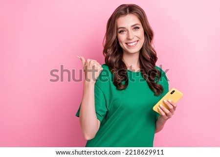 Portrait of cheerful nice gorgeous woman with wavy hairdo wear green t-shirt indicating empty space isolated on pink color background