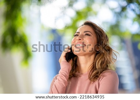 Close up portrait smiling young woman talking with mobile phone outdoors