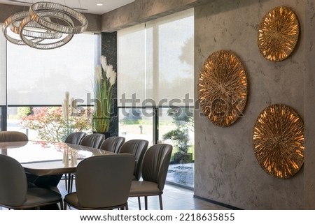 Roller blinds in the interior. Automatic solar shades large size on the window. Modern interior with wood decor panels on the wall. Green plants in hi-tech flower pots. Electric curtains for home.  Royalty-Free Stock Photo #2218635855