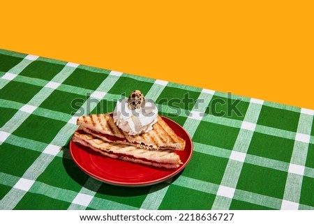 Surreal cake. Perfectionism and colorful minimalism. Meat sandwich, fried toast and raw quail egg on plaid tablecloth background. Food pop art photography. Vintage, retro 80s, 70s style.