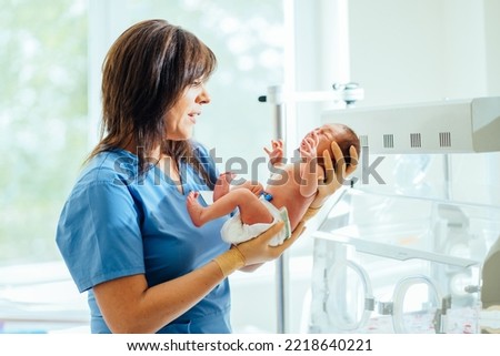 Health care concept. Doctor neonatologist calming down a crying baby holding newborn infant baby girl in hospital. Medical checkup. Royalty-Free Stock Photo #2218640221