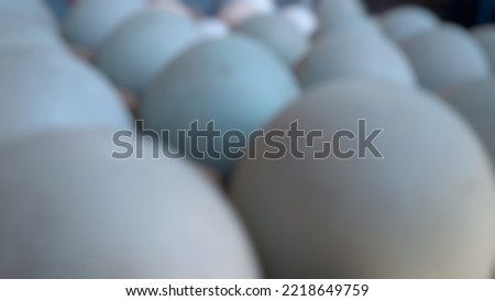 Vivid defocused image of duck eggs neatly arranged in a rustic rack, creating a captivating visual composition. Ideal for creative design projects.