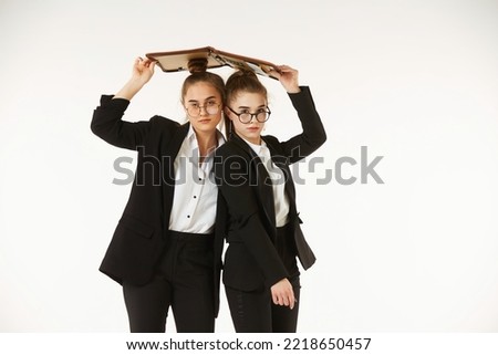 Two girls in office clothes. Under one roof. Pure white background. The concept of business and corporate relationships in the enterprise.