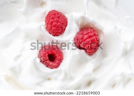 Fresh raspberries in the yoghurt or cream. Top view.