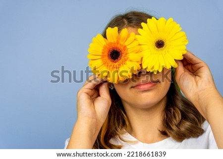 A happy pretty girl closes her eyes with yellow gerbera flowers